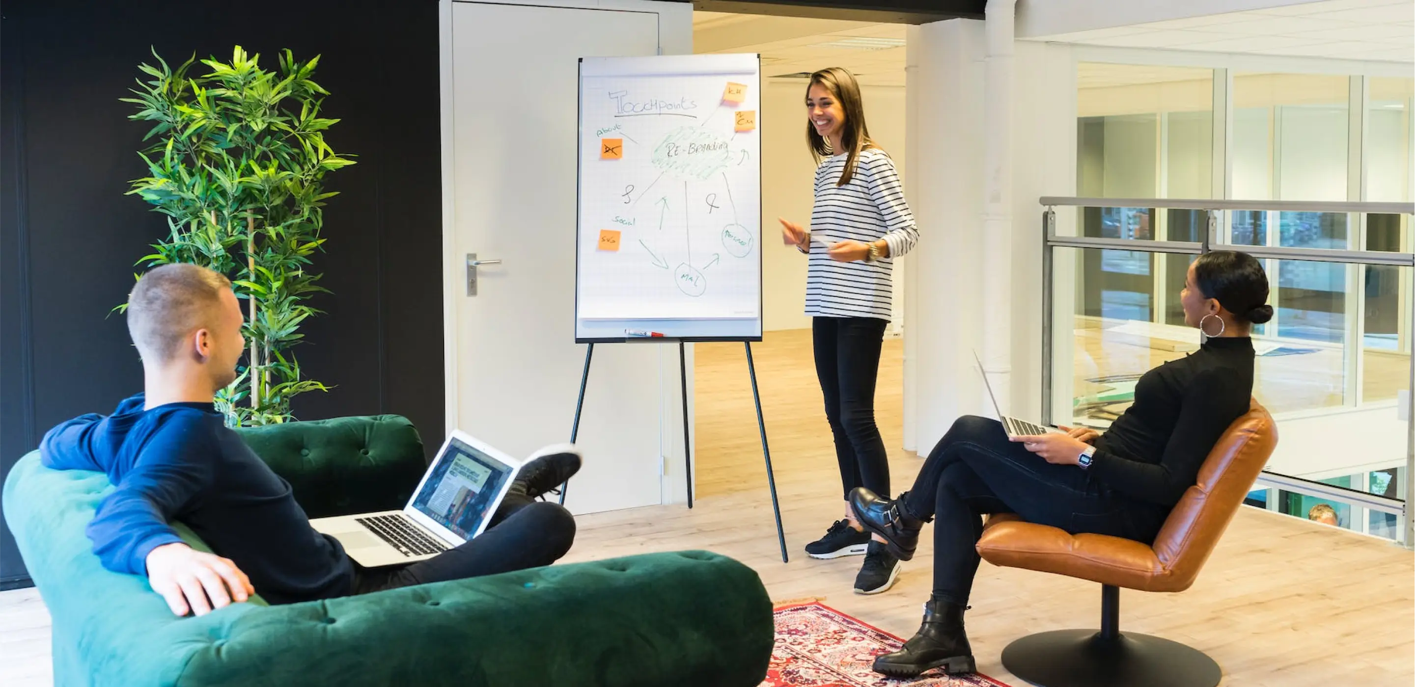 2 people listening while sitting while a women explaining a diagram