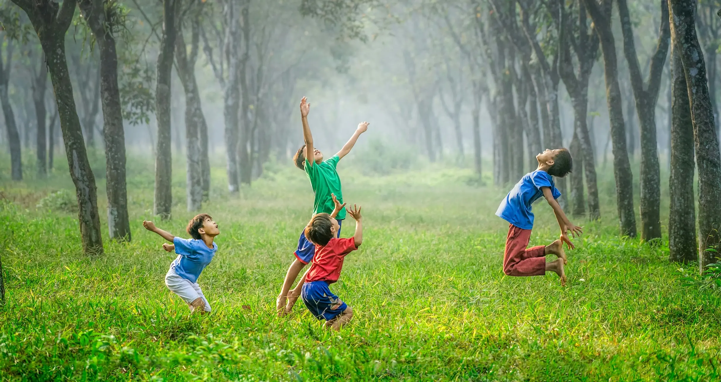 Four children jumping in the green woods