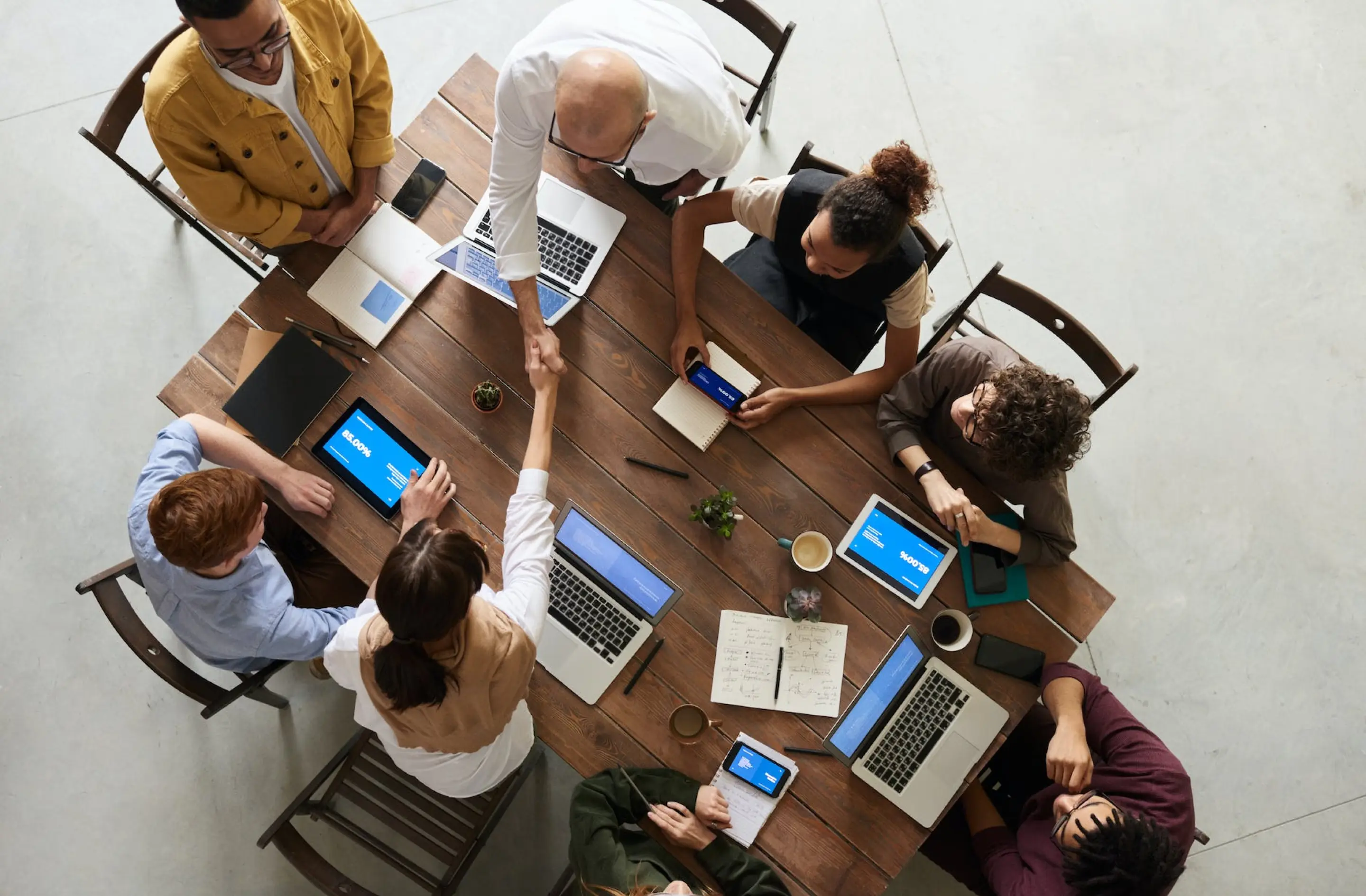 People in a meeting and two of them shaking hand, photo was taken from above angle