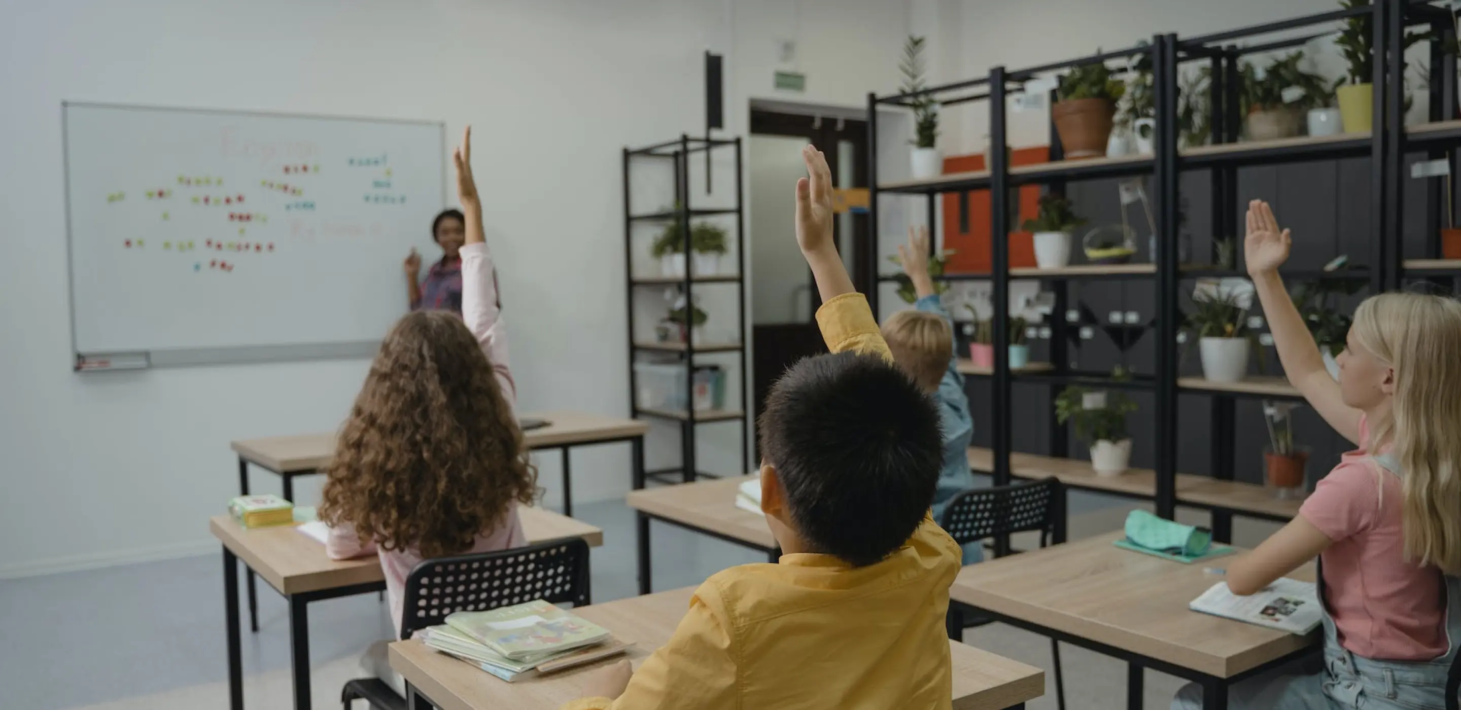 A classroom situation where several raising their hand