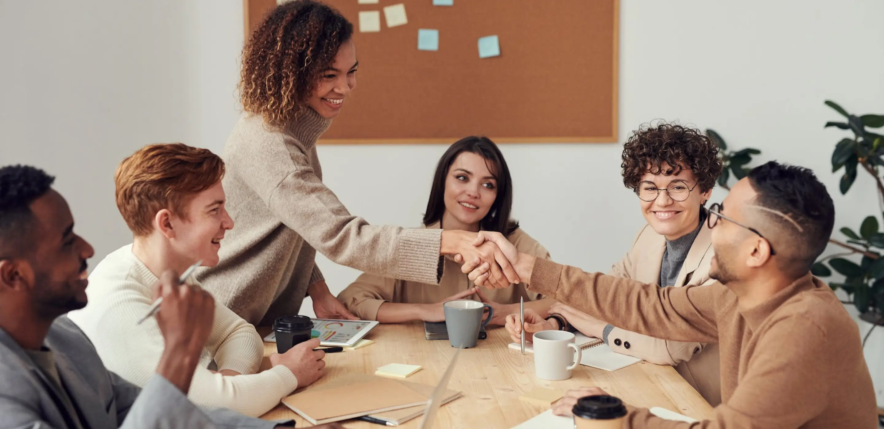 Several people in a meeting, 2 of them are shaking hand